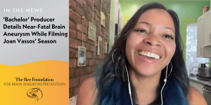 A smiling woman with blue-tinted hair and headphones is on a video call. Text on the left discusses a Bachelor producers near-fatal brain aneurysm and features The Bee Foundation for brain aneurysm prevention.