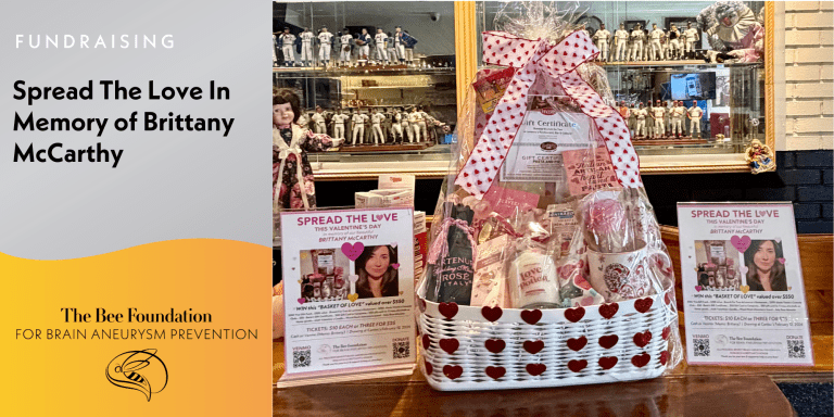 A white basket with heart cutouts holds gift items and sits on a bar counter. Signs promote The Bee Foundations fundraiser, Spread the Love in Memory of Brittany McCarthy, with raffle and ticket info displayed.