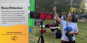 A smiling woman holds a bell near a digital race timer at an outdoor event. Text describes Ebony Richardson’s recovery from a brain aneurysm and her advocacy for brain aneurysm awareness with The Bee Foundation.