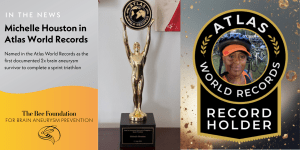 A graphic announcing Michelle Houston’s inclusion in Atlas World Records for being the first documented two-time brain aneurysm survivor to complete a sprint triathlon, featuring a trophy and Michelle’s photo with the Atlas Record Holder badge.