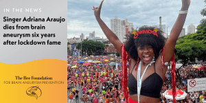 A woman in a festive costume with arms raised smiles at a colorful outdoor carnival, with a large crowd and city buildings in the background. Text reports her death from a brain aneurysm six years after lockdown fame.