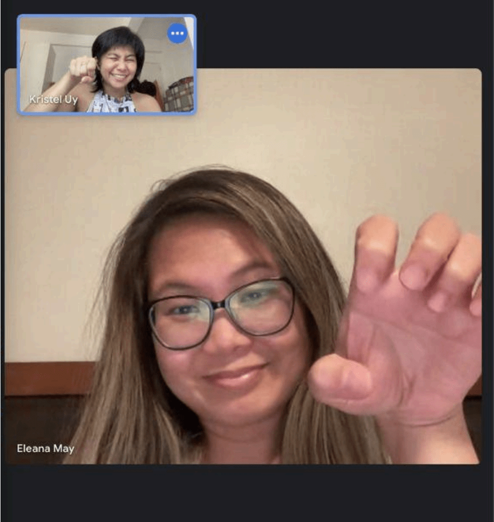 Two women video chatting, each smiling and making a playful claw gesture with their hand. The woman in the main frame has glasses and long hair; the woman in the small inset is laughing.