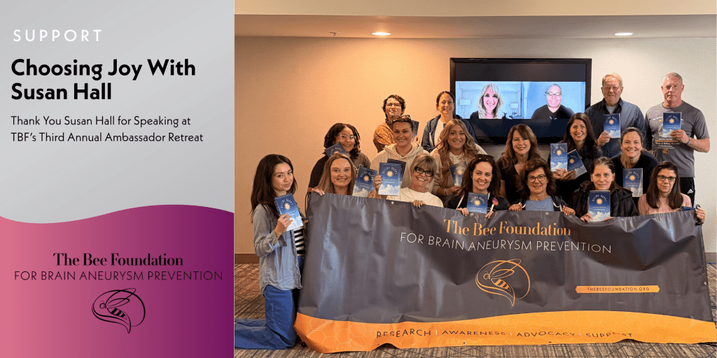 A group of people pose indoors holding booklets, standing behind a banner for The Bee Foundation for Brain Aneurysm Prevention. A screen shows others joining virtually. Text reads “Choosing Joy With Susan Hall” and thanks her for speaking.