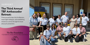 A group of smiling people wearing matching white shirts pose outside a building under a sign for The Bee Foundations Third Annual TBF Ambassador Retreat, supporting brain aneurysm prevention.