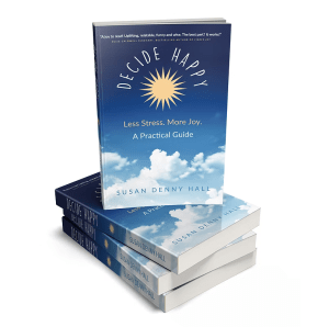 A stack of four copies of the book Decide Happy: Less Stress. More Joy. A Practical Guide by Susan Denny Hall, featuring a blue sky, clouds, and a yellow sunburst on the cover.